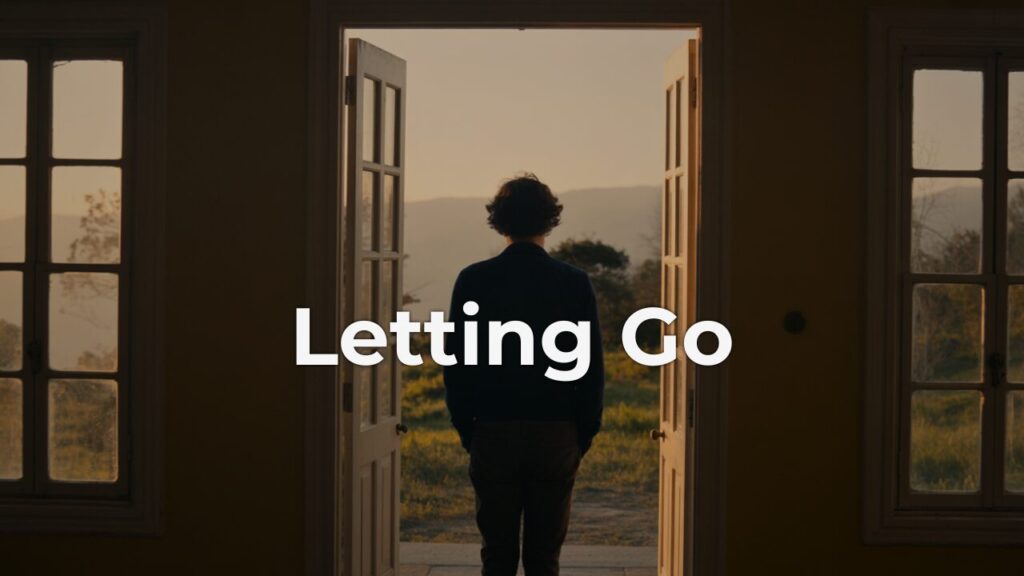 A person standing in a doorway, quietly letting go and stepping toward morning light