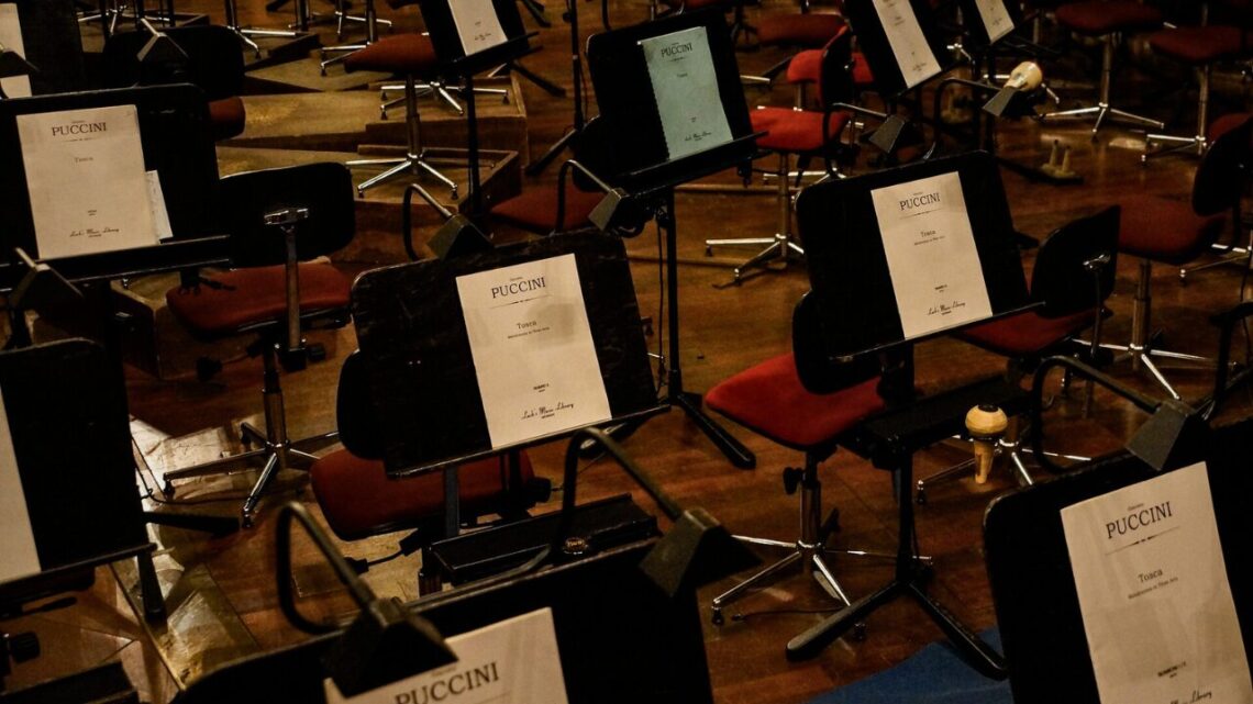 An empty orchestra pit in a quiet auditorium, bathed in soft natural light.