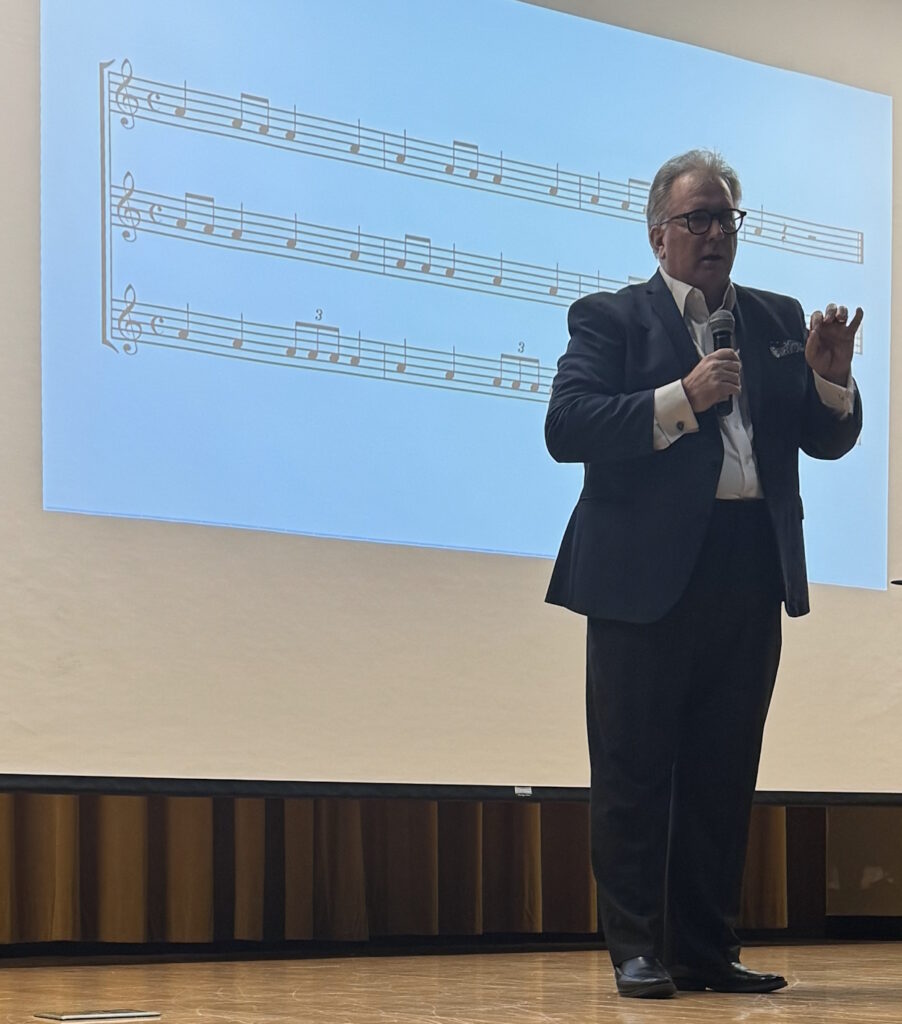 Stephen P. Brown gesturing while teaching pattern recognition through musical notation at PMI Tampa Bay, January 2026