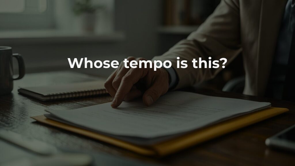A professional's hand resting deliberately on a document in a manila folder on a dark wooden desk, a notebook and mug softly blurred in the background, overlay text reading "Whose tempo is this?"