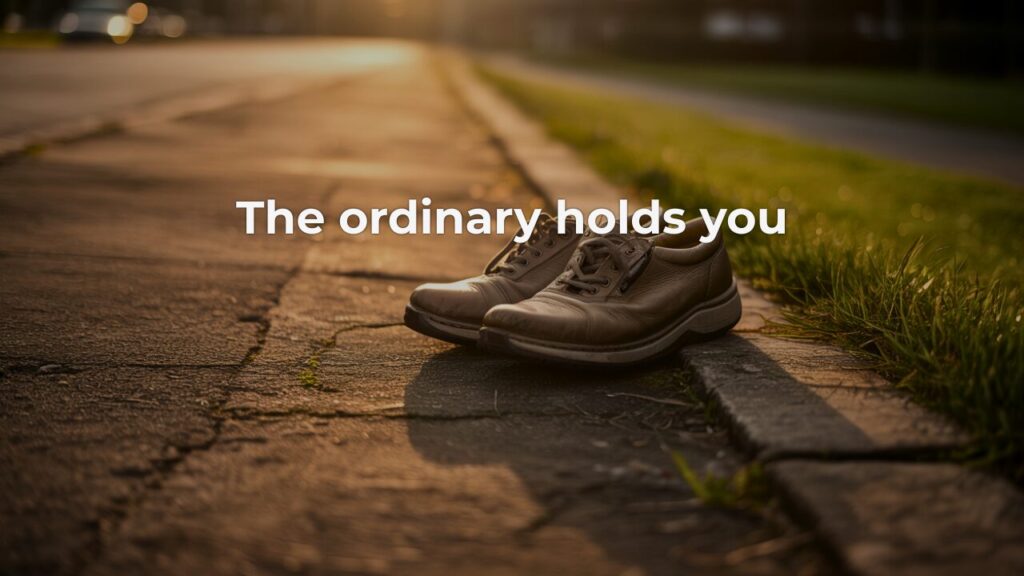 Worn leather walking shoes resting on a cracked pavement edge beside a grass verge, bathed in warm early morning light, with the overlay text "The ordinary holds you" — evoking the quiet faithfulness of ordinary disciplines.