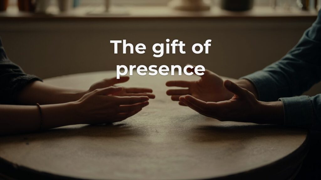 Two pairs of hands resting open on a worn wooden table, turned toward each other in a moment of full presence and attentive listening.