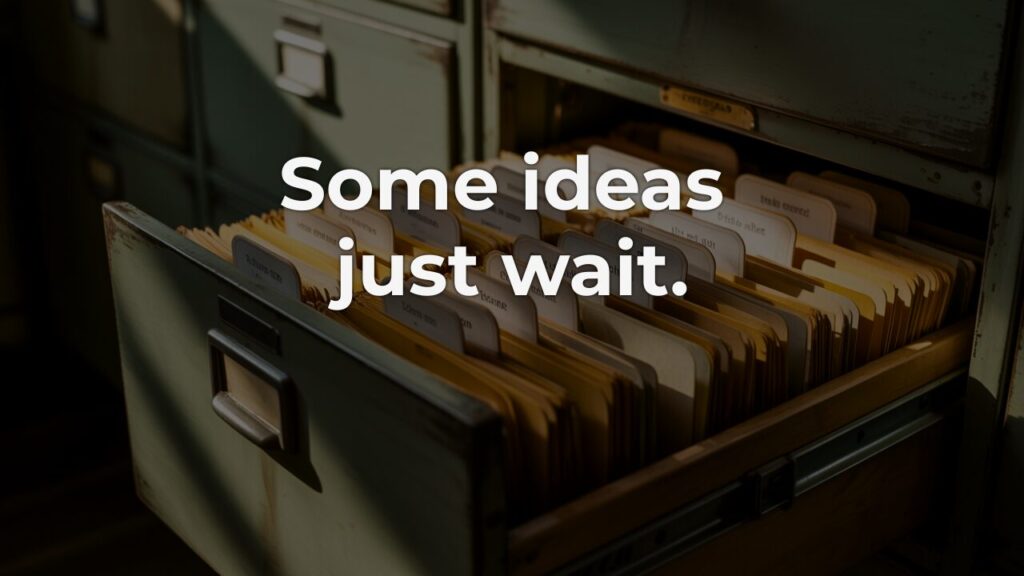 An open vintage filing cabinet drawer filled with neatly arranged manila folders, overlaid with the words "Some ideas just wait." — evoking the quiet discipline of holding creative ideas without pressure.
