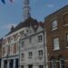 Rochester High Street in Kent, England, lined with Georgian brick buildings and red, white, and blue bunting under a bright summer sky.