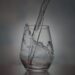Water pouring into a clear glass, capturing a mid-splash moment against a softly lit, dark background.