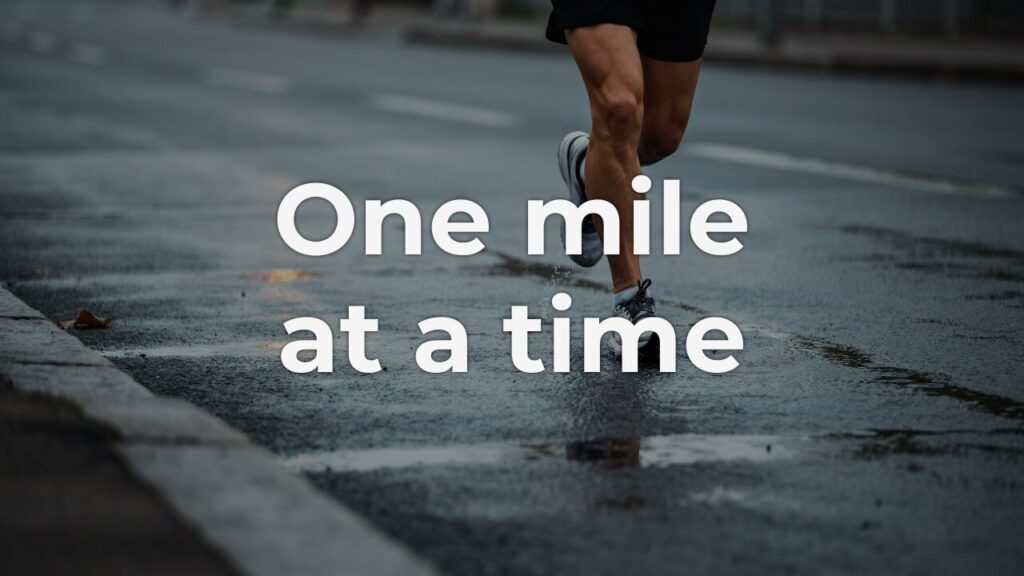 A runner's legs mid-stride on wet pavement in early morning light, capturing the steady effort of running one mile at a time.